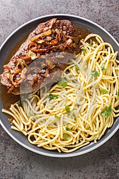 Austrian Steak Zwiebelrostbraten With Crispy Onions and spaetzle pasta closeup on the plate. Vertical top view