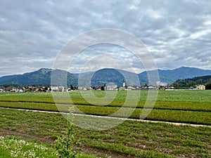 Austrian village with fields and mountains under cloudy sky