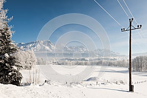 Austrian Winter Wonderland with mountains, a power pole, fresh snow and haze