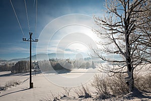 Austrian Winter Wonderland with mountains, a power pole in fresh snow and haze