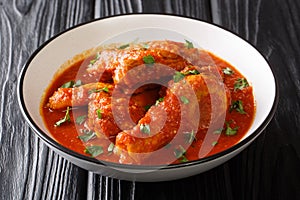 Authentic Ayam Masak Merah Recipe made with chicken pieces that are doused in a spicy tomato sauce close-up in a bowl. Horizontal photo