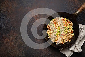 Authentic Chinese and Asian fried rice with egg and vegetables in wok top view on rustic concrete table background