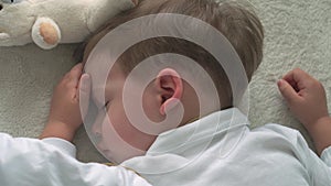 Authentic close up of cute caucasian little preschool toddler child boy 2-3 years sleep sweetly in comfortable white bed
