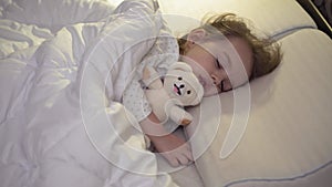 Authentic close up of cute caucasian little preschool toddler child girl 3-4 year sleep sweetly in comfortable white bed