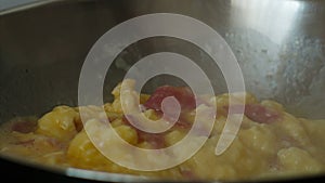 Authentic closeup food shot showing the preparation of scrambled eggs with bacon in a frying pan