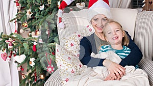 Authentic family christmas portrait in front of xmas tree. Smiling mother and daughter at christmas.