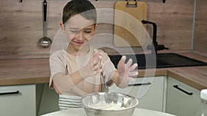 Authentic family. A happy kid is playing with flour, clapping her hands. Baby and mom in the kitchen. mother's day