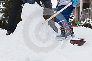 Authentic family winter fun. Family building a snowman in their frontyard. Candid real people lifestyle image. photo