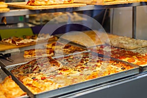 Authentic Italian pizza in a restaurant display window. Various pizzeria in glass window display. Focus on pizza with