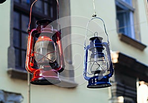 Authentic lamp-lanterns of red and blue hanging on the background of the windows of the building, concept of authentic objects