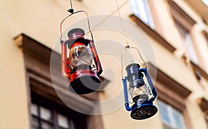 Authentic lamp-lanterns of red and blue hanging on the background of the windows of the building, concept of authentic objects