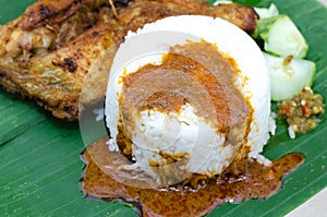 Authentic malaysian dish, steam rice served with deep fried chicken leg, cucumber and chili paste on banana leaf