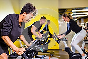 authentic mixed race group training on exercise bikes teamwork