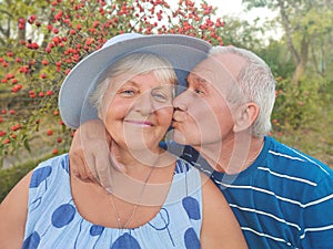 Authentic outdoor shot of aging couple having fun in the garden and blessed with love. During their game man is trying to kiss his