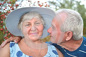 Authentic outdoor shot of aging couple having fun in the garden and blessed with love. During their game man is trying to kiss his