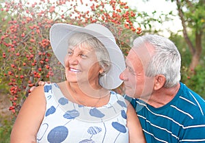 Authentic outdoor shot of aging couple having fun in the garden and blessed with love. During their game man is trying to kiss his