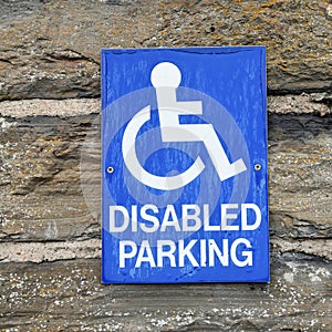 Authentic painted blue and white disabled parking sign on rustic stone wall