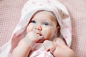 Authentic portrait of 4 months baby girl wrapped in towel after bath.