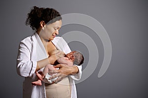 Authentic woman, happy young mother, holding her newborn baby suckling at her breast, feeding him with mother milk