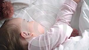 Authentic portrait cute caucasian little infant chubby baby girl or boy in pink sleep with teddy bear on white bed