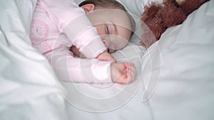 Authentic portrait cute caucasian little infant chubby baby girl or boy in pink sleep with teddy bear on white bed