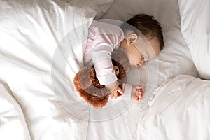 Authentic portrait cute caucasian little infant chubby baby girl or boy in pink sleep with teddy bear on white bed