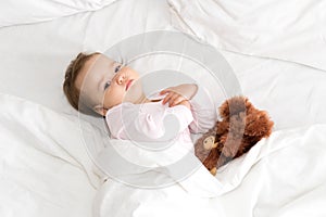 Authentic portrait cute caucasian little infant chubby baby girl or boy in pink sleepy upon waking with teddy bear