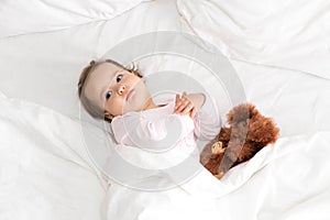 Authentic portrait cute caucasian little infant chubby baby girl or boy in pink sleepy upon waking with teddy bear