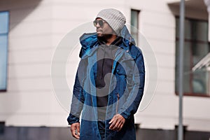 Authentic Portrait of handsome African American man walking in city, wearing stylish outfit parka coat, hoodie, knitted