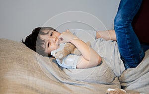 Authentic portrait Kid lying on safa biting his finger nails while watching TV, Little boy lying on couch bite his nails, Child