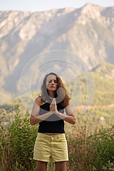 Authentic portrait of a woman in her thirties, hands in namaste