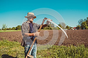 Authentic rural farmer check sharpness scythe. Agriculture worker. Vegetable garden. Farm implements. Rustic background. Work