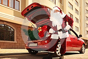 Authentic Santa Claus  car with fir tree and bag full of Christmas gifts outdoors, low angle view