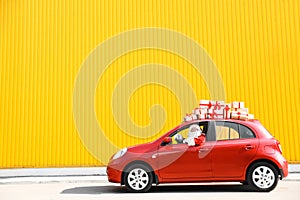 Authentic Santa Claus driving red car with gift boxes