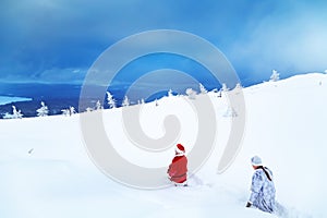 Authentic Santa Claus and a girl in winter clothes are walking on a snowy mountain