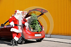 Authentic Santa Claus near red car with gift boxes