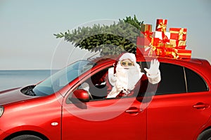 Authentic Santa Claus with presents and fir tree on roof driving modern car