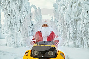 Authentic Santa Claus is riding a snowmobile through the winter