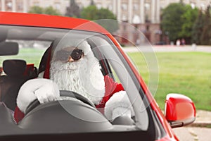 Authentic Santa Claus in sunglasses driving car