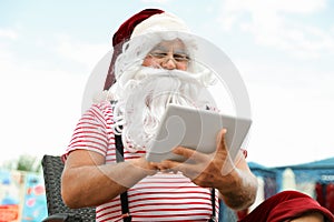 Authentic Santa Claus with tablet working on lounge char
