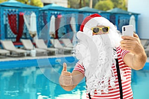 Authentic Santa Claus taking selfie near pool