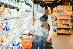 Authentic shot of mother and son wearing medical masks to protect themselves from disease making shopping for groceries