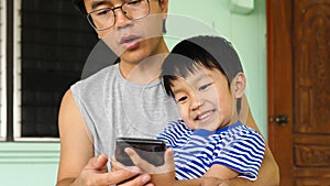 Authentic son and father looking on smartphone outdoor