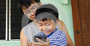 Authentic son and father looking on smartphone outdoor with happy smiling face.