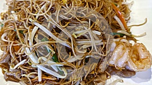 Authentic stir-fry rice noodles with shrimp and bean sprout. Close-up on a plate.