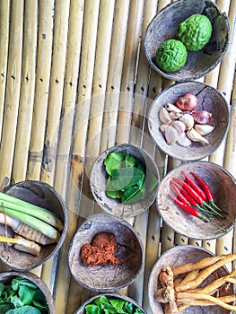 Authentic Thai red curry past recipe with ingredients in coconut shells on bamboo table