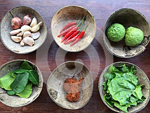 Authentic Thai red curry past recipe with ingredients in coconut shells on old wooden