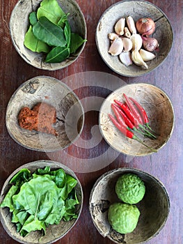 Authentic Thai red curry past recipe with ingredients in coconut shells on old wooden