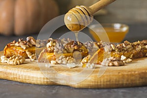 Authentic view of a pumpkin baked with slices of honey and walnuts on a wooden kitchen board.