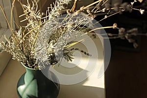 Authentic winter still life with dry lavender flowers in a vase on a wooden windowsill.